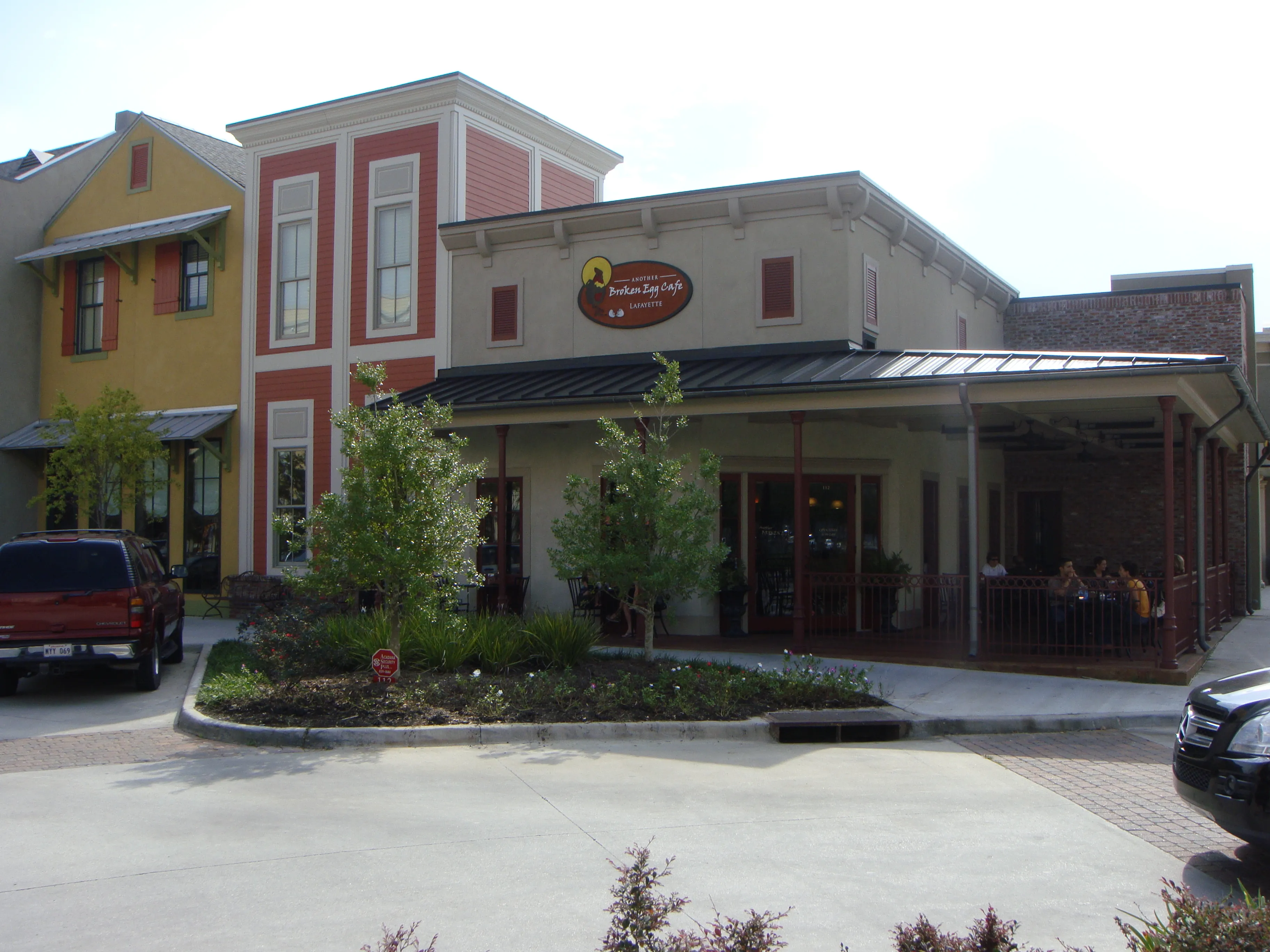 Front elevation of the Another Broken Egg Cafe, showing the two-story red-and-cream façade and metal patio canopy.