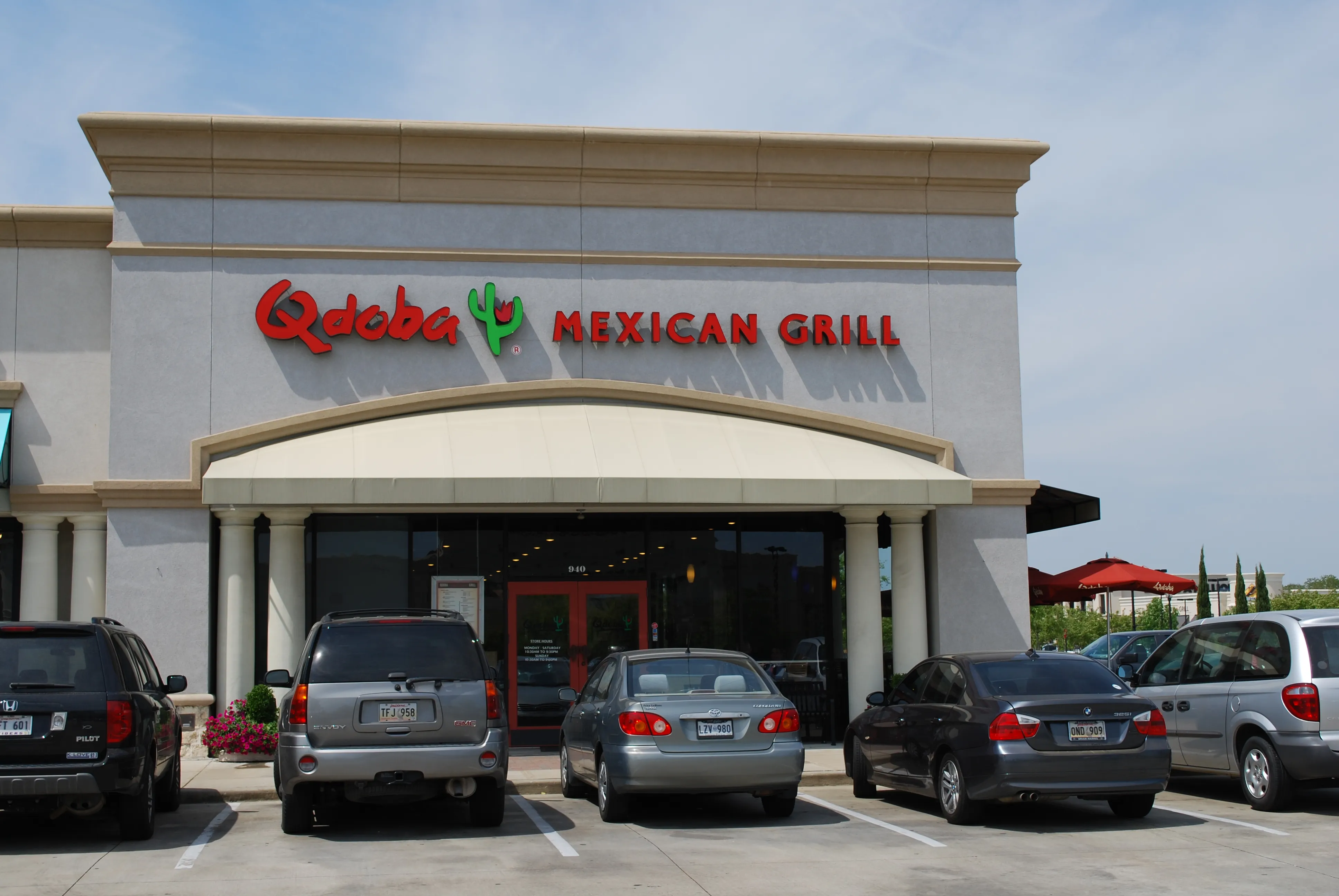 Qdoba Mexican Grill storefront with its columned entrance canopy and illuminated red sign.